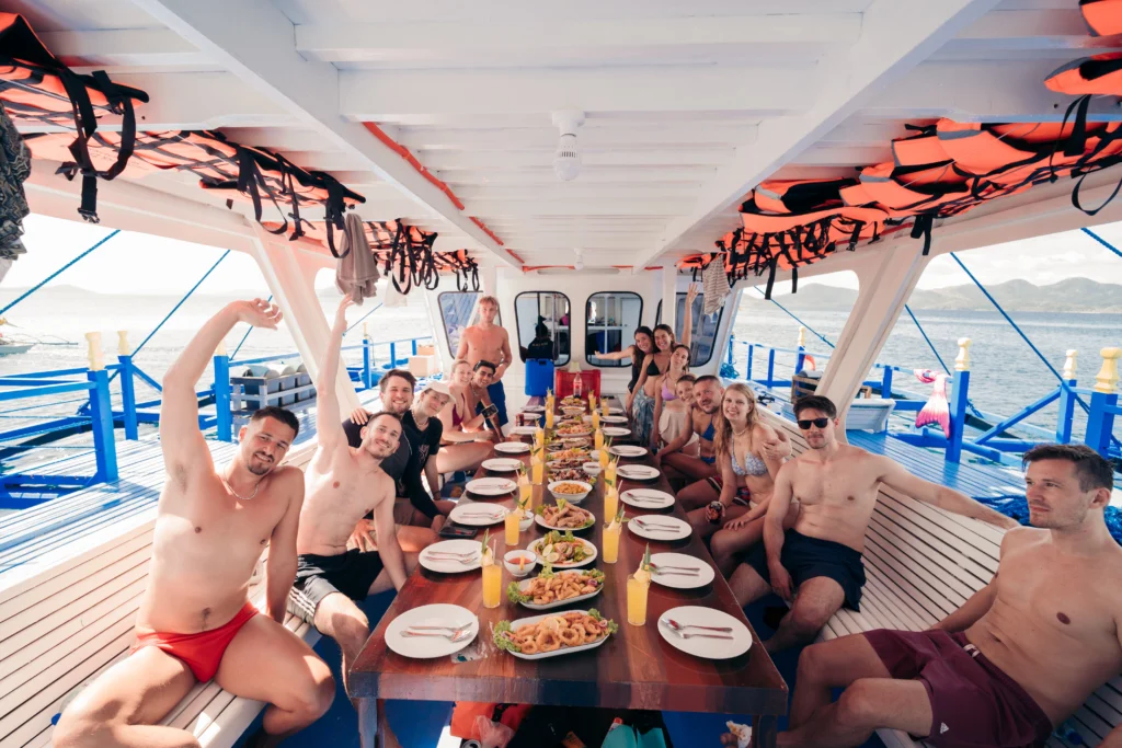Travelers jumping off the bow of a boat into crystal clear waters during a 3-day Palawan island hopping adventure.