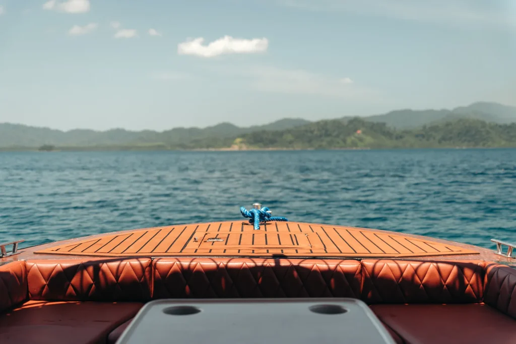 First-person view from the wooden bow of the YOHAK luxury speedboat cruising toward an El Nido island.