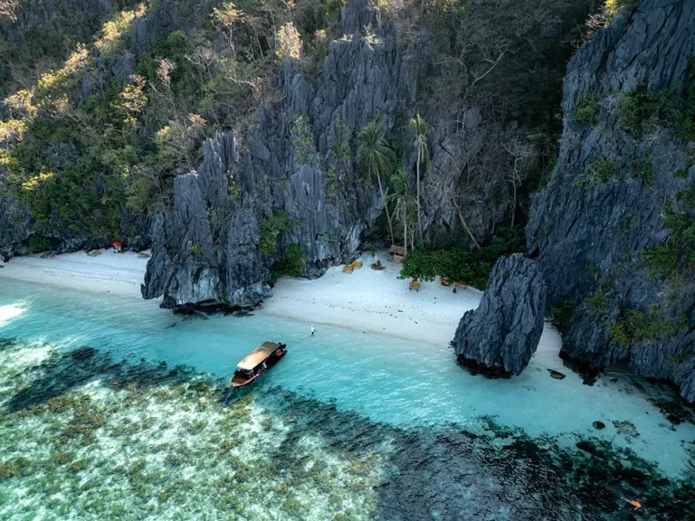 Aerial view of the Yohak luxury speedboat anchored in the clear turquoise waters of Entalula Beach, El Nido.