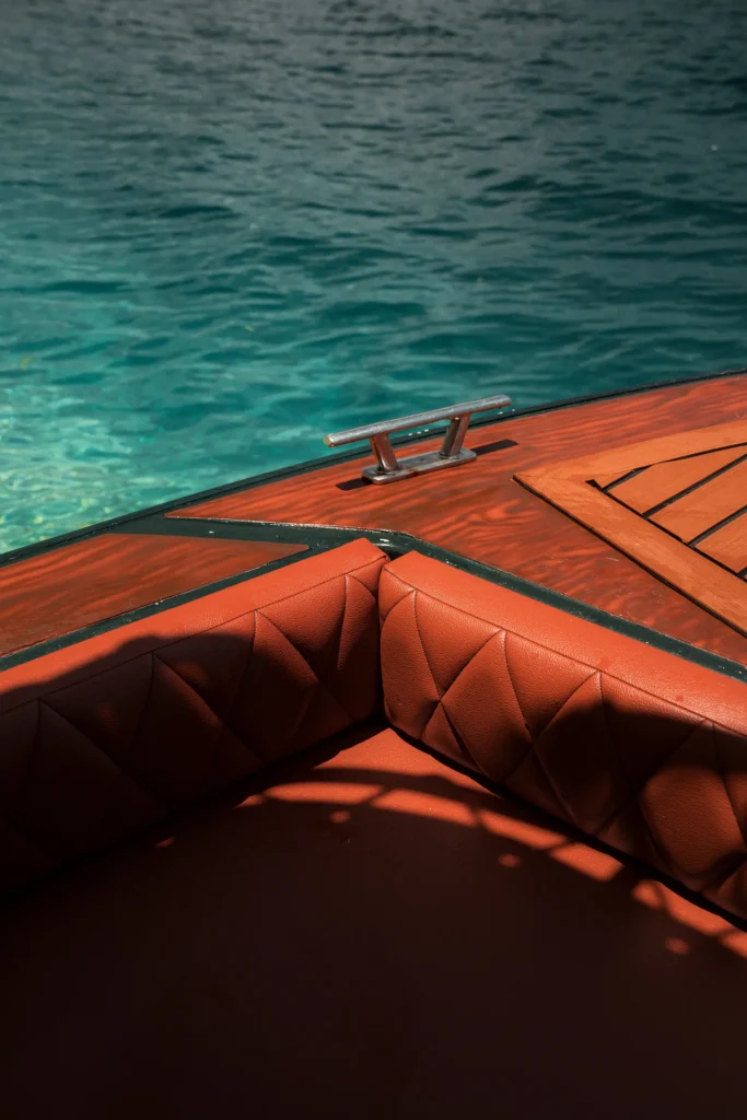 Detail vertical shot of the premium tan leather corner seat and wooden deck of a Yohak speedboat in El Nido, Palawan.