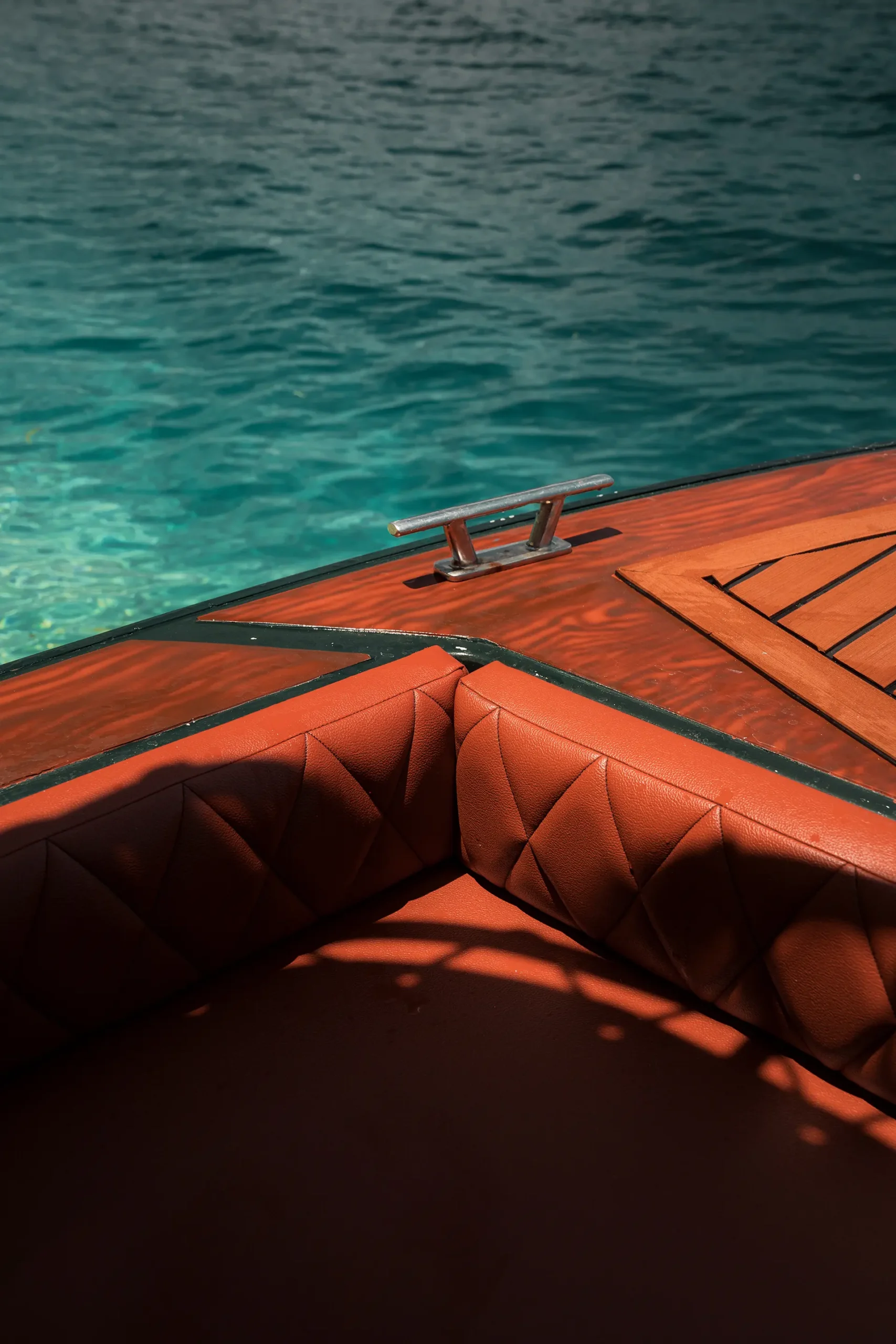 Detail vertical shot of the premium tan leather corner seat and wooden deck of a Yohak speedboat in El Nido, Palawan.