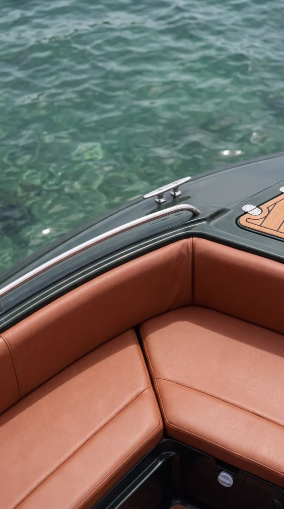 Brown cushioned seating inside a Yohak speedboat beside clear turquoise water in El Nido, Palawan.