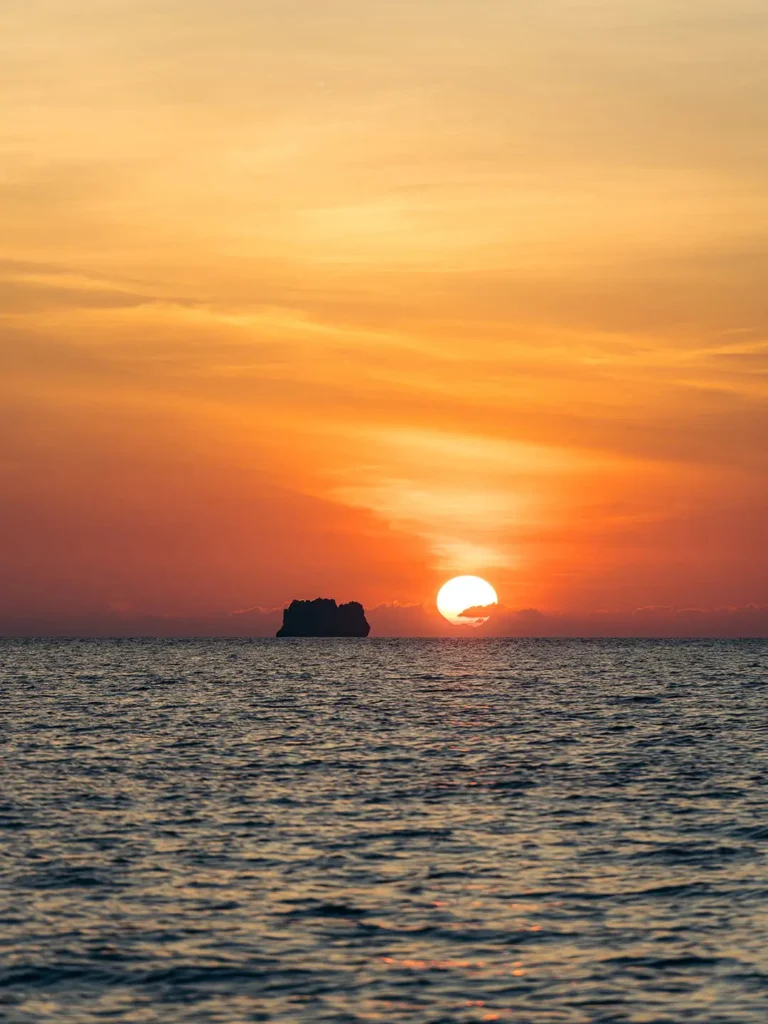 Sunset over El Nido waters with an island silhouette framed against a golden sky.