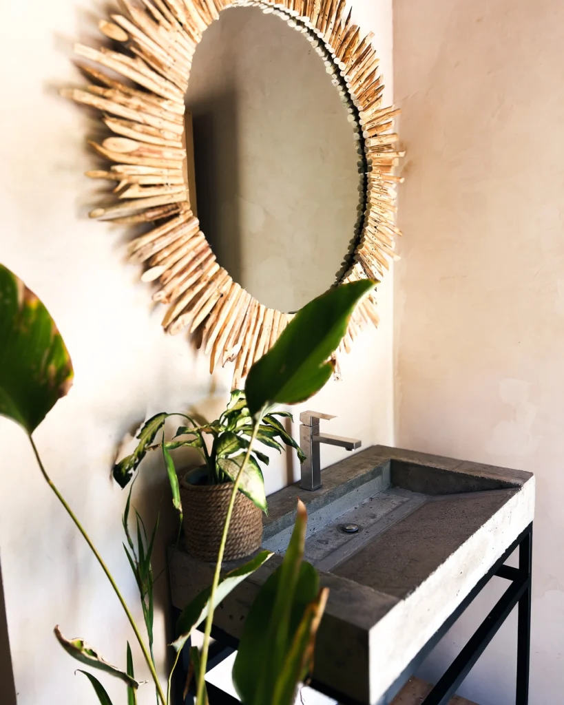 Concrete sink and driftwood sunburst mirror in a bathroom at Parada Beach Camp Palawan