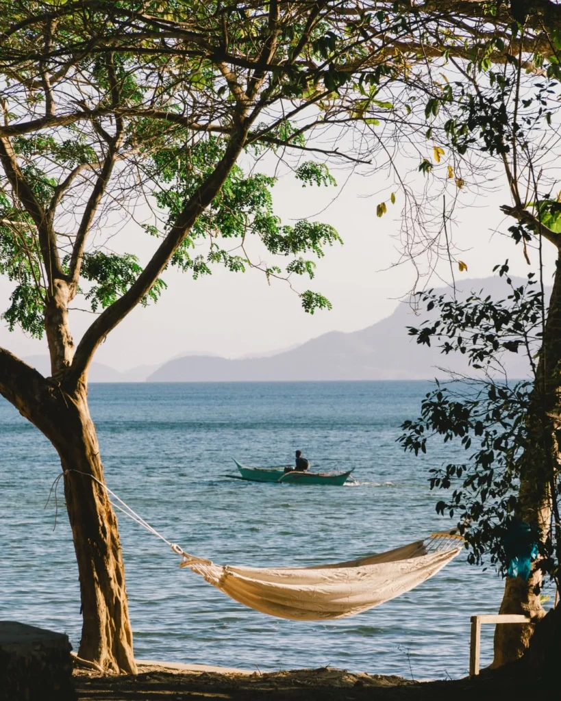 Beachfront hammock with a bangka boat and island view at Parada Beach Camp Linapacan