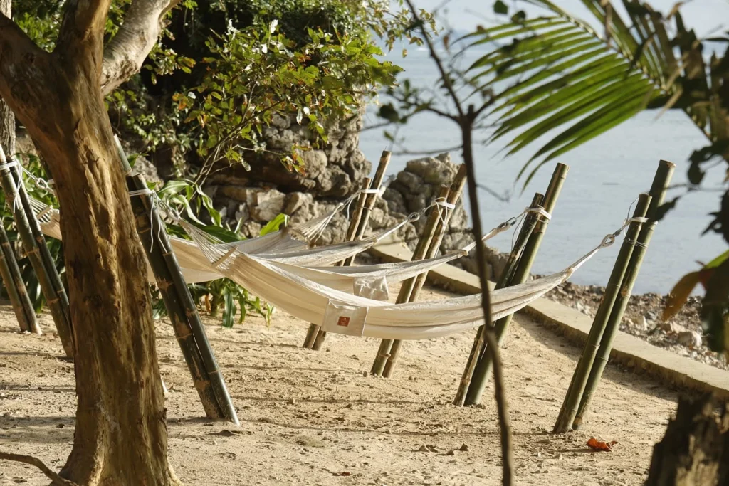 Row of beachfront hammocks on bamboo posts by the sea at Parada Beach Camp Linapacan