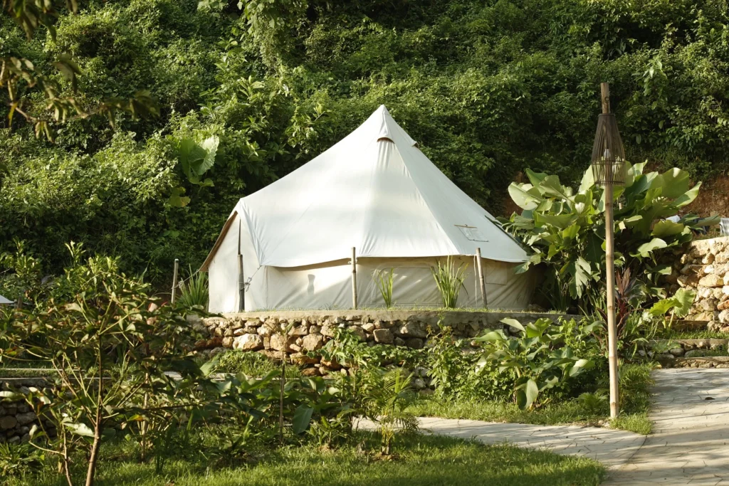 Canvas glamping bell tent on a stone terrace amid tropical gardens at Parada Beach Camp