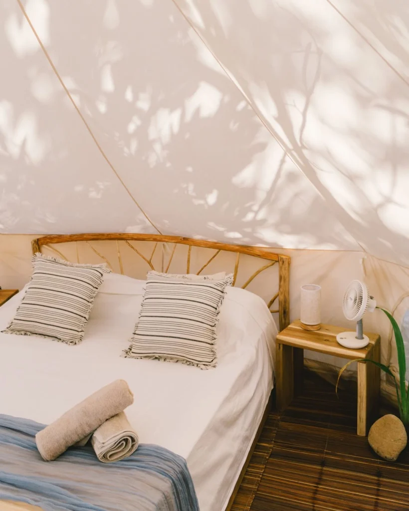 Glamping bell tent interior with cozy bed and striped pillows at Parada Beach Camp Palawan