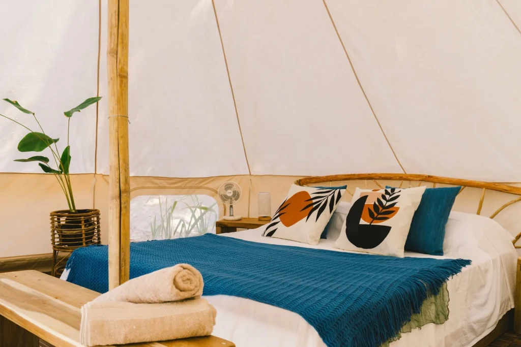 Bell tent interior with blue throw and botanical pillows at Parada Beach Camp Linapacan