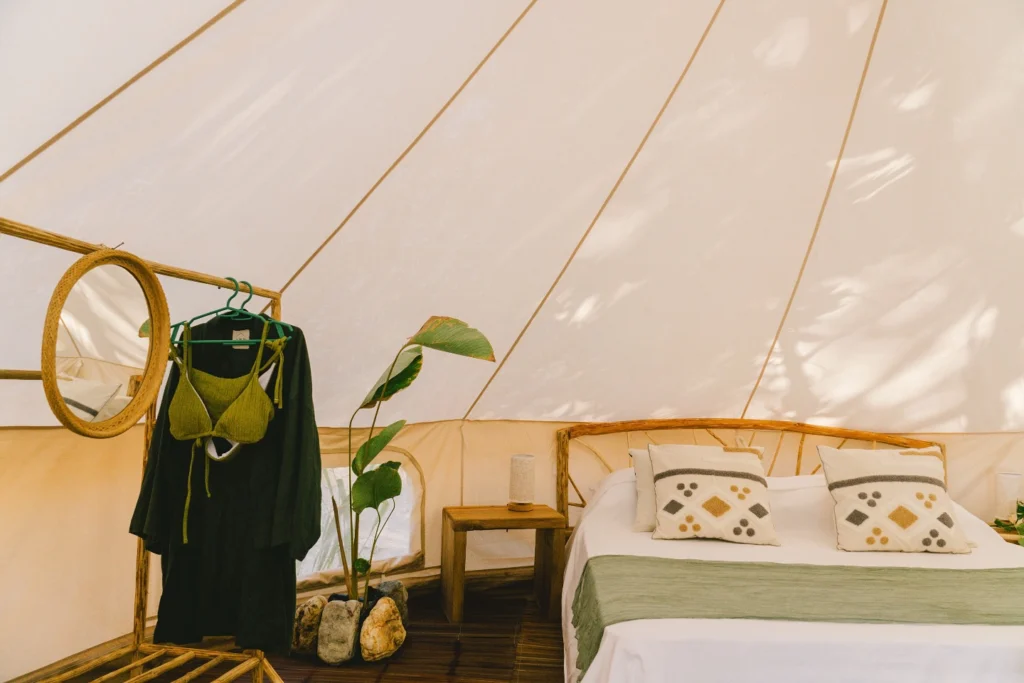 Bright bell tent interior with bed mirror and clothing rack at Parada Beach Camp Palawan