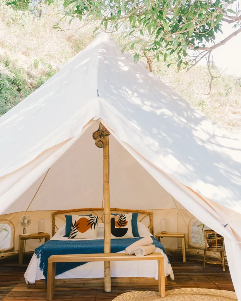 Glamping bell tent framed by its open entrance and a tree at Parada Beach Camp Palawan
