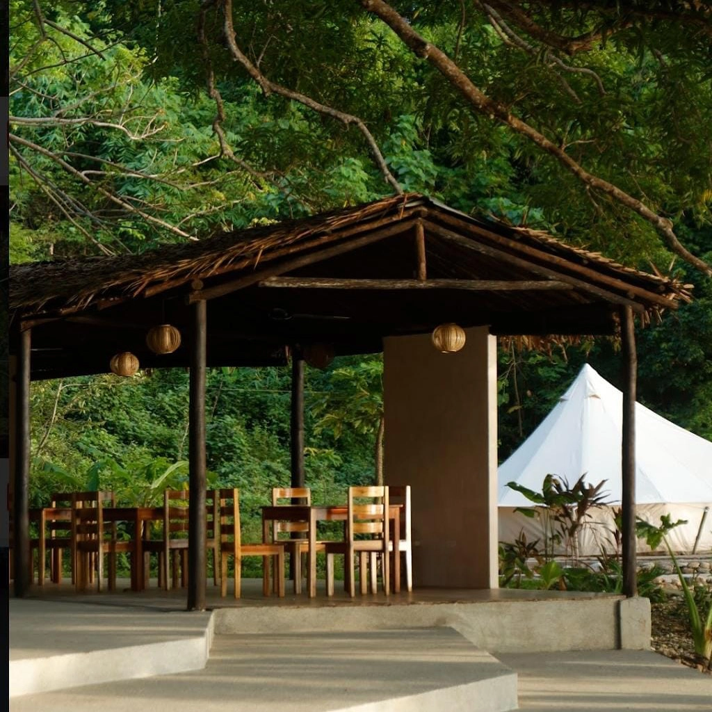 Thatched open-air dining pavilion beside a glamping tent at Parada Beach Camp Linapacan