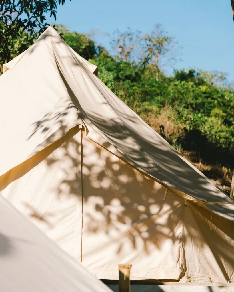 Cream canvas glamping bell tent with leaf shadows at Parada Beach Camp Linapacan