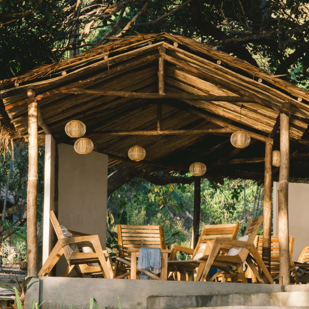 Thatched lounge pavilion with wooden lazy chairs and rattan lanterns at Parada Beach Camp Linapacan