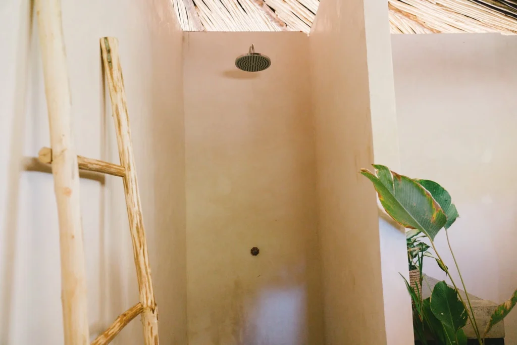 Open-air rain shower with rustic ladder and plants at Parada Beach Camp Linapacan