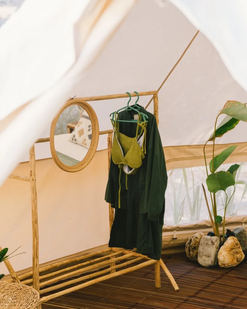 Bell tent interior with clothing rack mirror and bed at Parada Beach Camp Linapacan