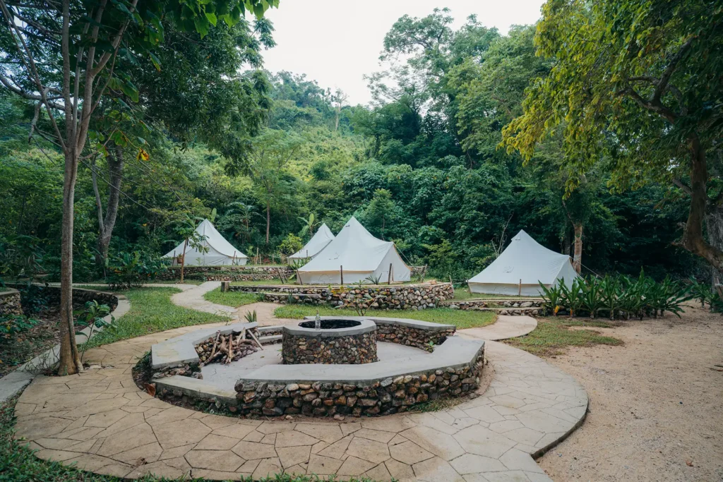 Glamping tents surrounding a stone fire pit at Parada Beach Camp