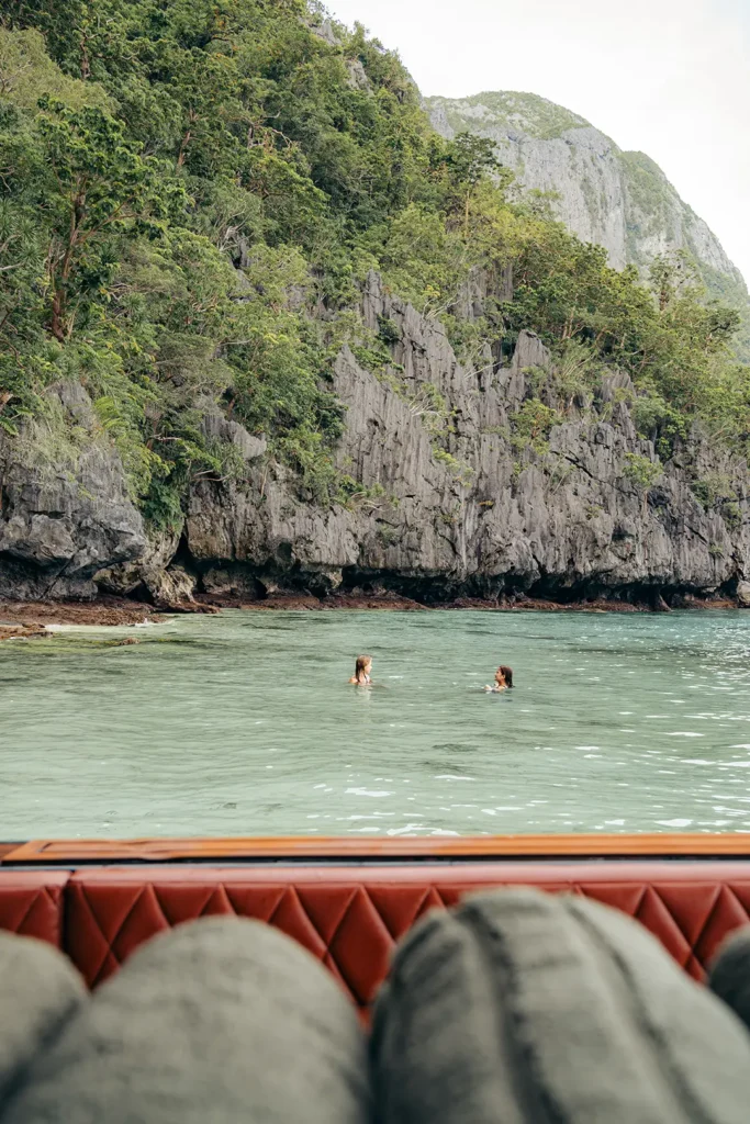 Guests swimming beside dramatic limestone cliffs during a Yohak island expedition