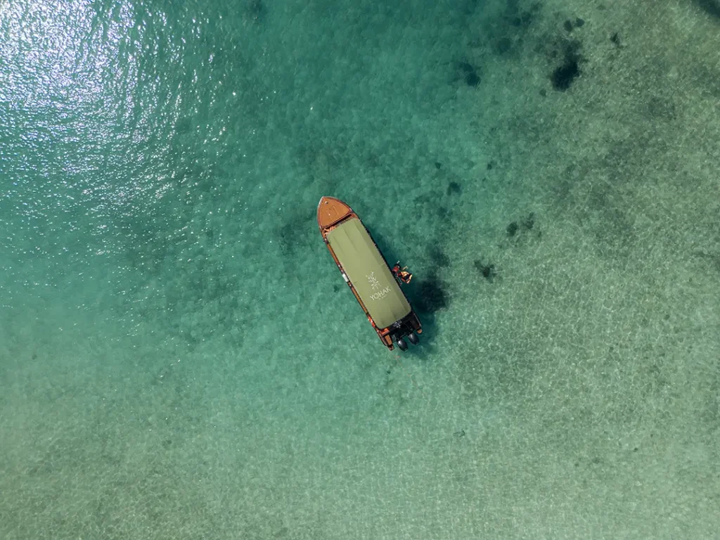 Aerial view of a Yohak boat floating over clear tropical water in Palawan