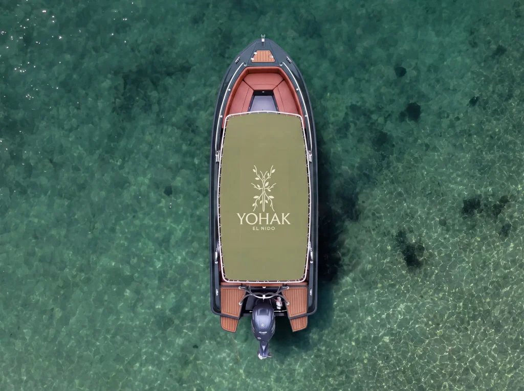 Aerial view of a Yohak El Nido speedboat floating over clear turquoise water, used for shared island tours in Palawan.
